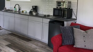 A modern kitchen with white cabinets, a stainless steel range hood, a microwave, and a toaster.