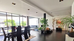 Un espace repas moderne avec une cloison en verre, des chaises noires et des plantes en pot.