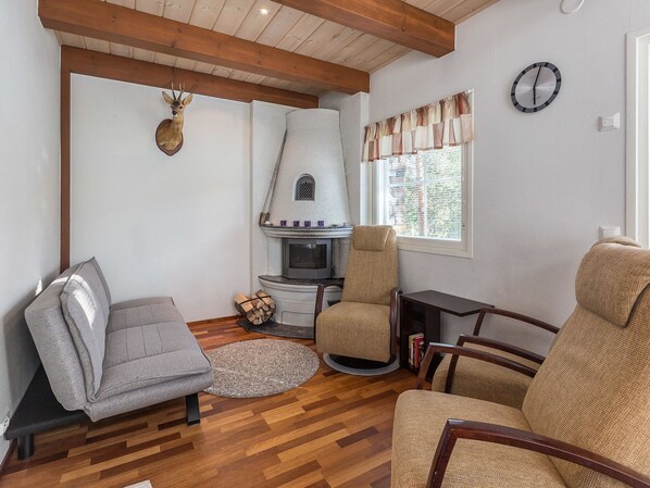 A cozy living room with a fireplace, wooden flooring, and comfortable seating.