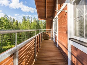 A wooden deck with a metal railing overlooking a forested area.