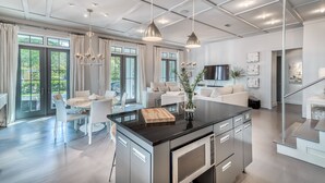 Una cocina moderna con una isla central, electrodomésticos de acero inoxidable e iluminación colgante.