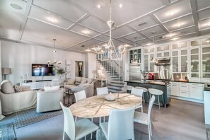 A modern living room with a marble dining table, white sofas, and a TV.