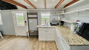 Una cocina con armarios blancos, encimera de granito, pileta integrada y ventana con vistas a zonas verdes.
