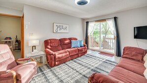 A living room with a red sofa, a white table, and a blue cushion. There is a sign on the wall that says "Gather". - Lakefront Family Retreat w/ Private Dock! (Rice Lake)