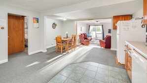 A spacious living area with a dining table and chairs, a kitchen with a refrigerator, and a cozy seating area with a red chair. - Lakefront Family Retreat w/ Private Dock! (Rice Lake)