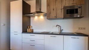 Una cocina moderna con armarios blancos, un microondas de acero inoxidable y un horno empotrado.