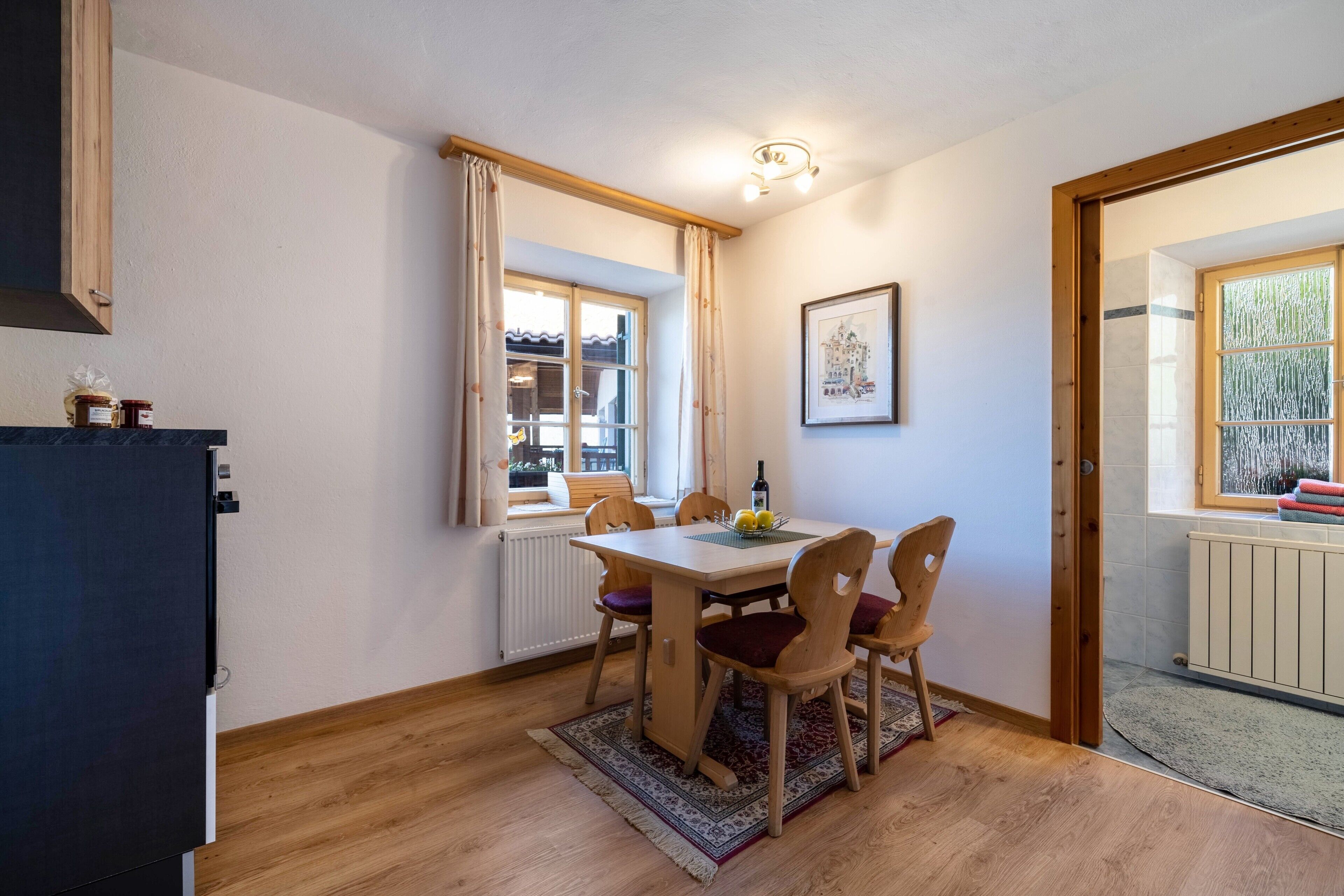 A dining area with a table, chairs, a radiator, and a window with curtains.