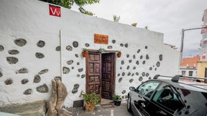 A white building with a wooden door, a welcome mat, and a sign above the door. - Holiday Apartment "Casa Amparo" with Terrace, Ocean View, Whirlpool & Wi-Fi (Icod de los Vinos)