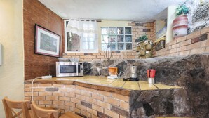 A kitchen with a brick backsplash, a microwave, a coffee maker, and wooden chairs. - Holiday Apartment "Casa Amparo" with Terrace, Ocean View, Whirlpool & Wi-Fi (Icod de los Vinos)