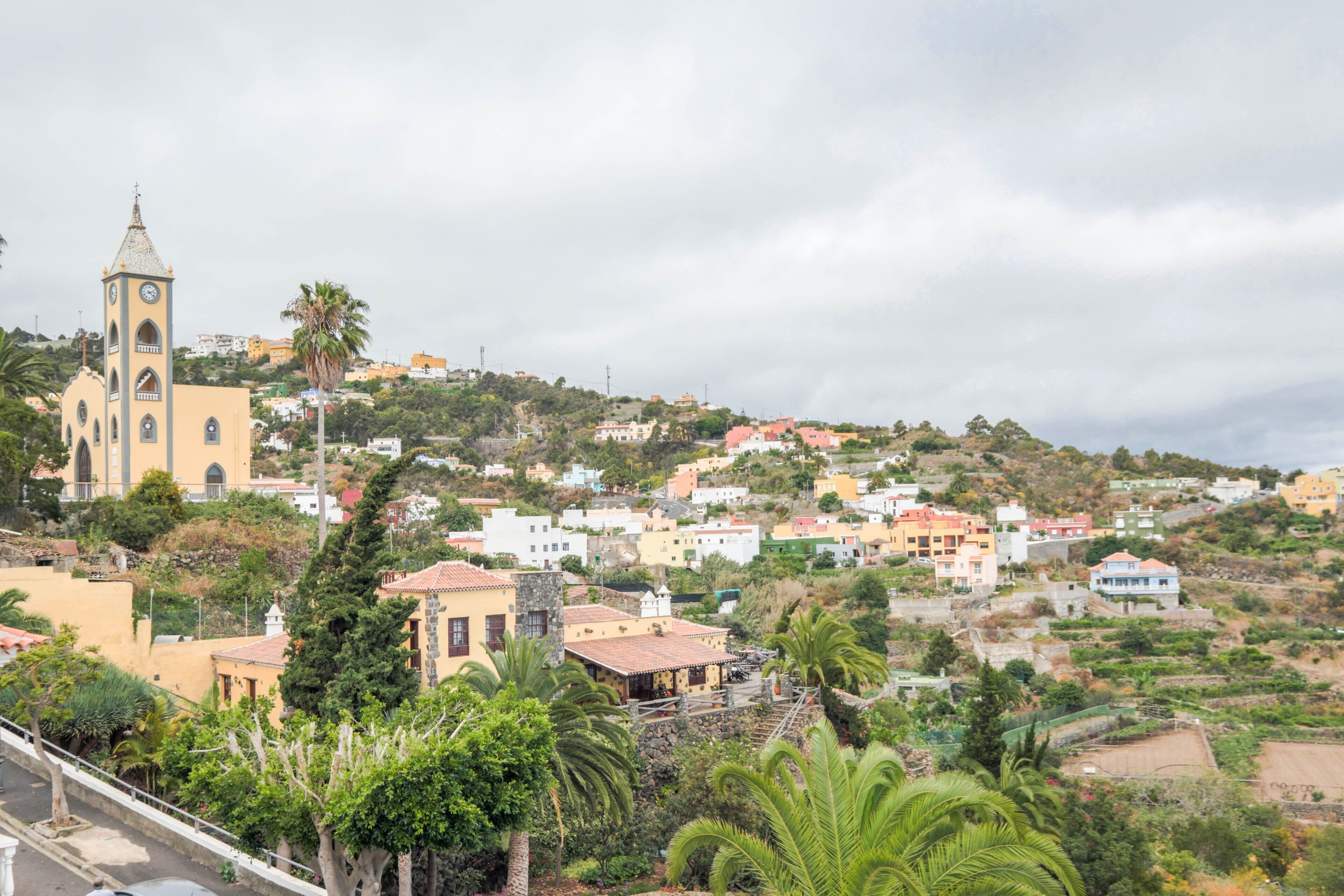 Un pueblo costero con una iglesia destacada, edificios residenciales y abundante vegetación.