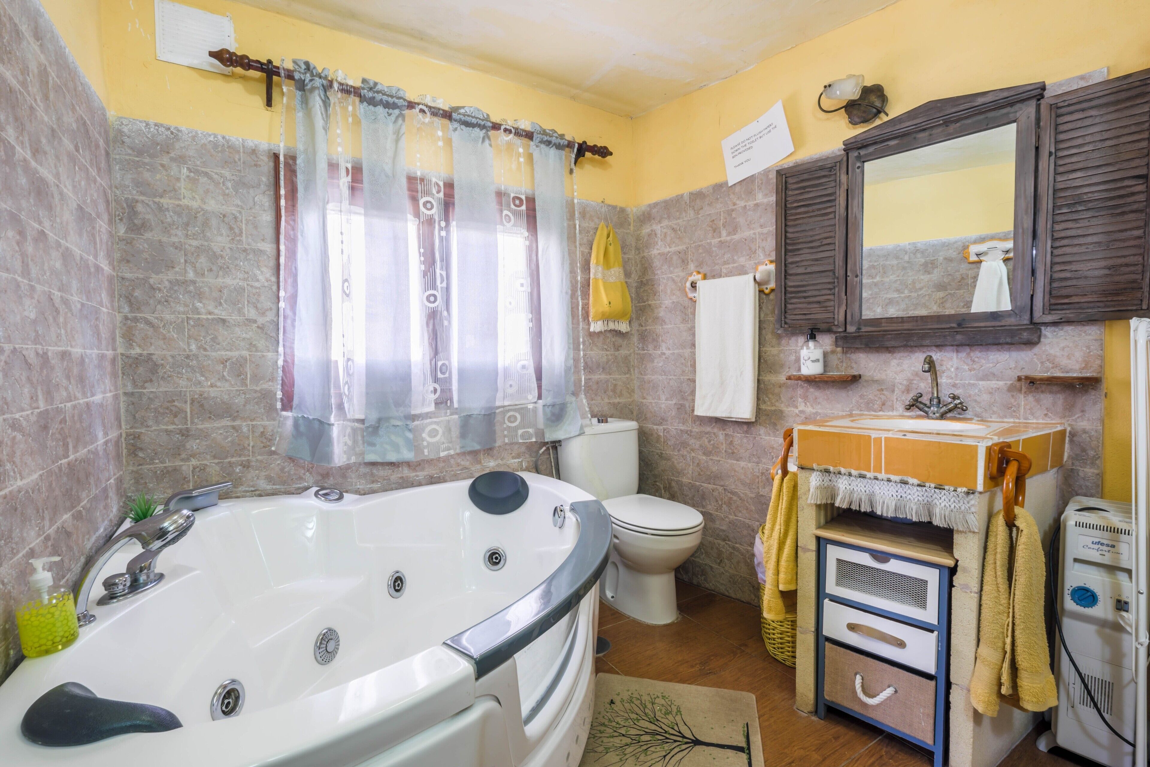 Un baño con bañera, inodoro, lavamanos y espejo.