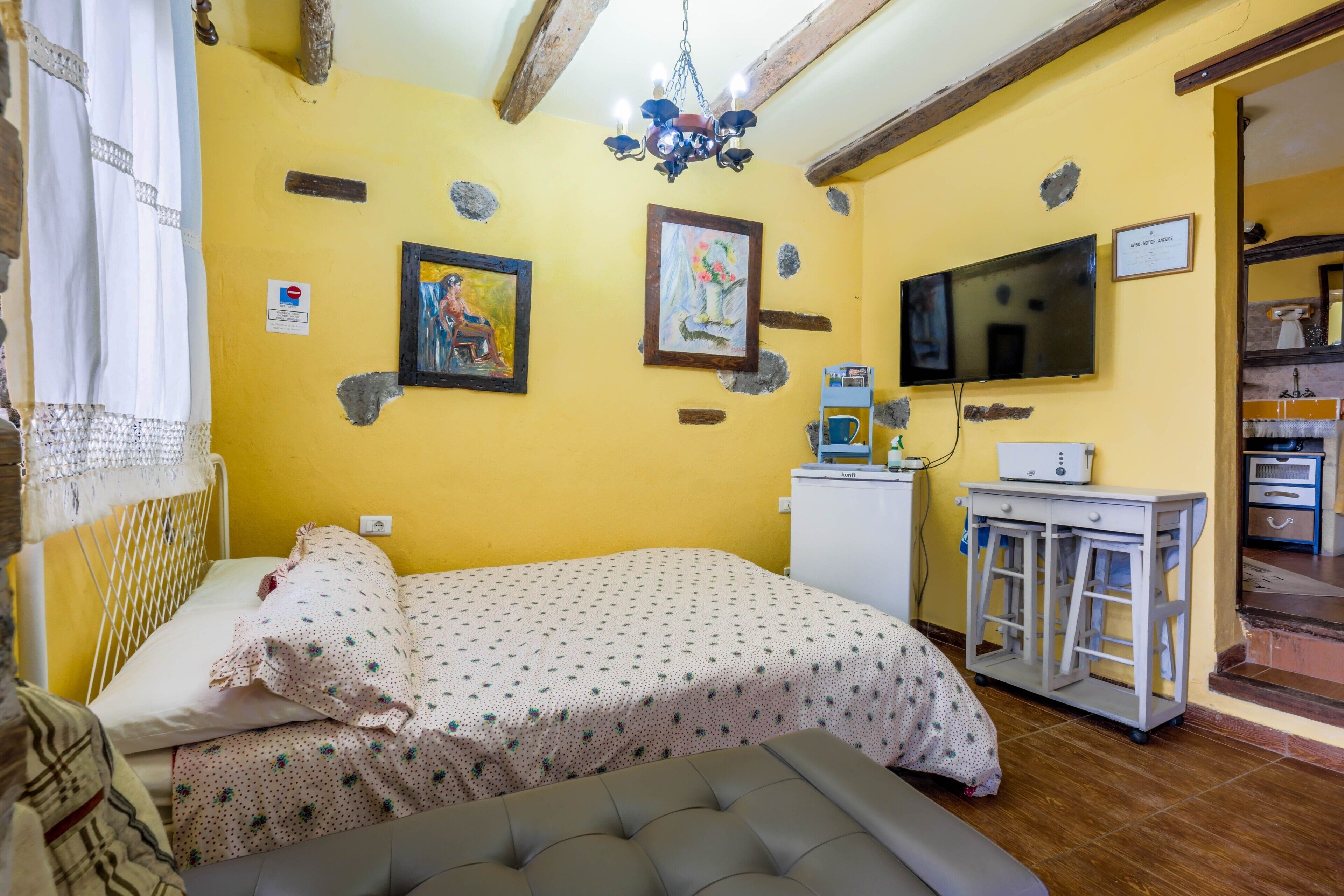 A room with a bed, a television, a desk, and a chair.