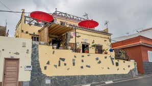 A building with a stone facade, a wooden door, and red umbrellas on the roof.