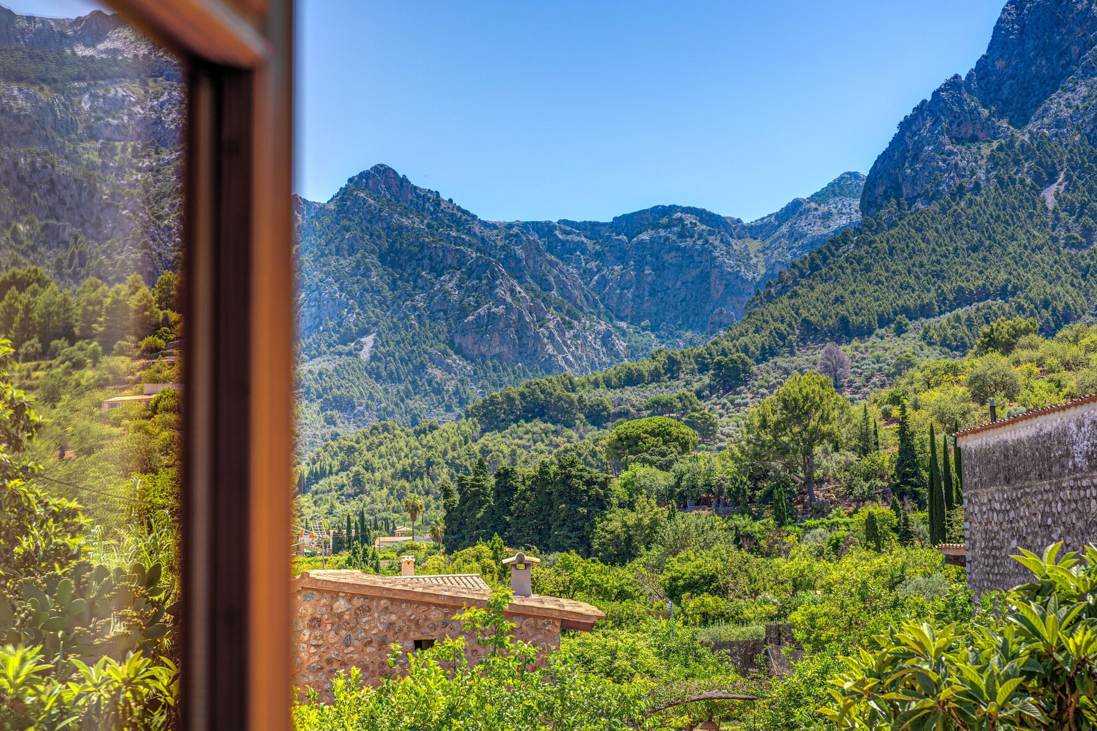 A mountainous landscape with a stone building and lush greenery.