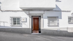 Un bâtiment avec une porte en bois, le chiffre « 7 » au-dessus, et des fenêtres grillagées.