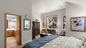 A bedroom with a bed, a desk, a chair, a wardrobe, and a window with a view of trees. - Newly Remodeled Townhouse, 2 Master Suites, Hot Tub, SHARC Passes, Bikes (Sunriver)