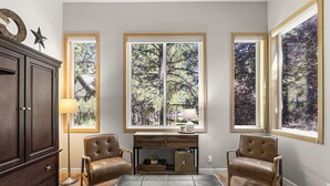 A room with a large window, a desk, two chairs, a cabinet, and a floor lamp. - Newly Remodeled Townhouse, 2 Master Suites, Hot Tub, SHARC Passes, Bikes (Sunriver)