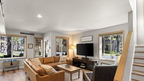 A living room with a sectional sofa, a coffee table, a TV, and a staircase. - Newly Remodeled Townhouse, 2 Master Suites, Hot Tub, SHARC Passes, Bikes (Sunriver)