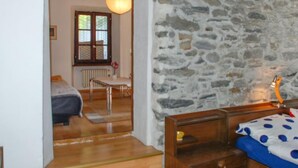 Ein Schlafzimmer mit Steinwand, Holzbett und einer Pendelleuchte.
