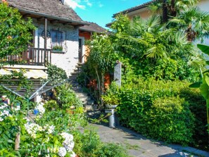 A stone staircase leading to a house with a balcony, surrounded by lush greenery and a clear blue sky. - Verzaschina by Interhome (Gordola)