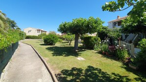 A residential street with houses, a paved walkway, and lush greenery.