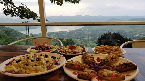 A table with various dishes and a scenic view through a window. - Miraya Hotel (Wai)