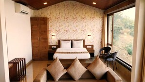 A bedroom with a bed, wooden wardrobe, and a sofa with cushions. - Miraya Hotel (Wai)
