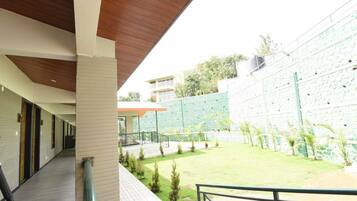 A covered outdoor area with a pathway leading to a building entrance, a small lawn, and a stone wall.