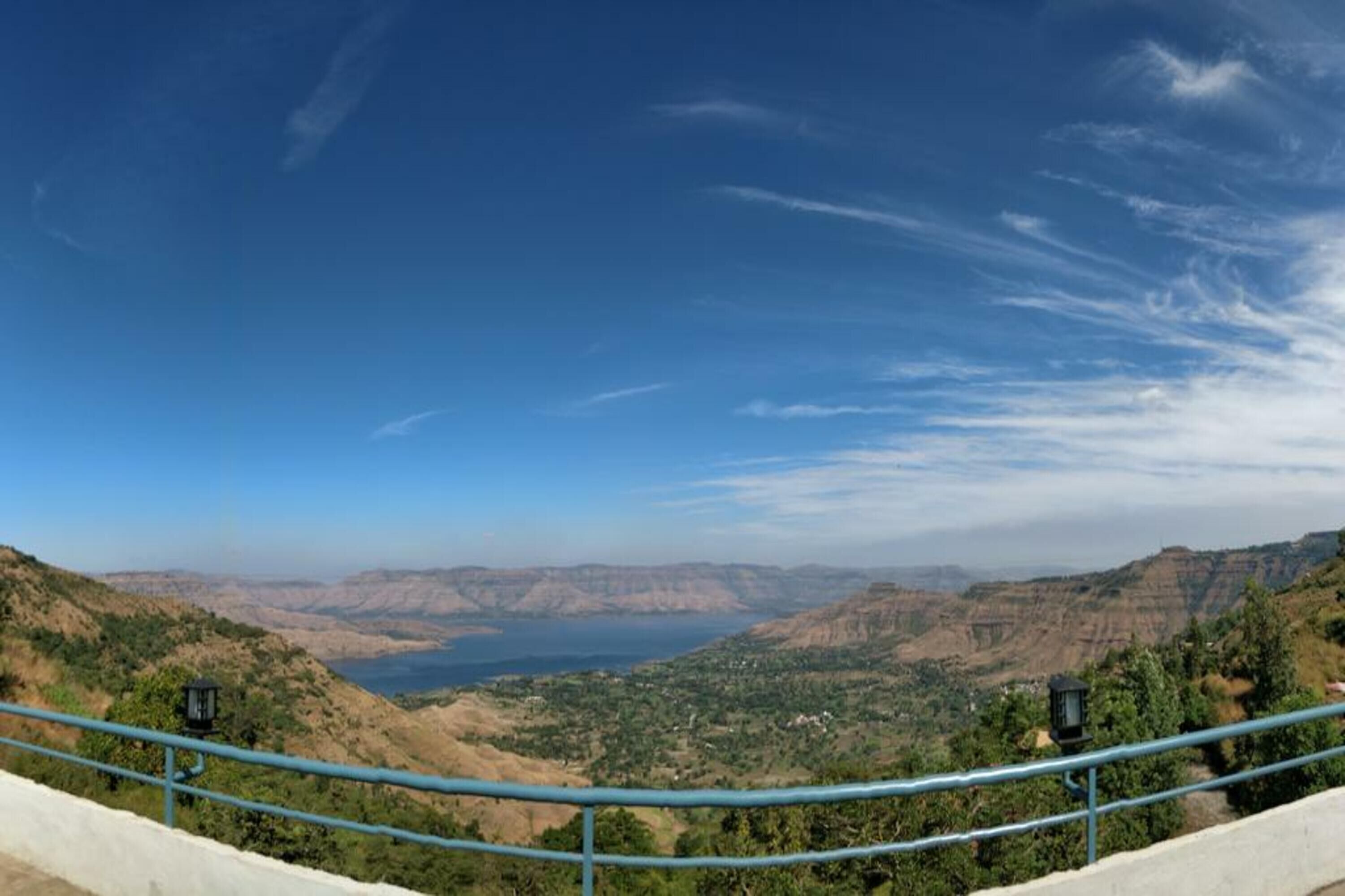 Een panoramisch uitzicht op een bergachtig landschap met een heldere lucht en een waterlichaam in de verte.