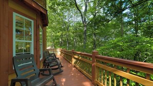 Une terrasse en bois, dotée de bancs, entourée d’arbres.