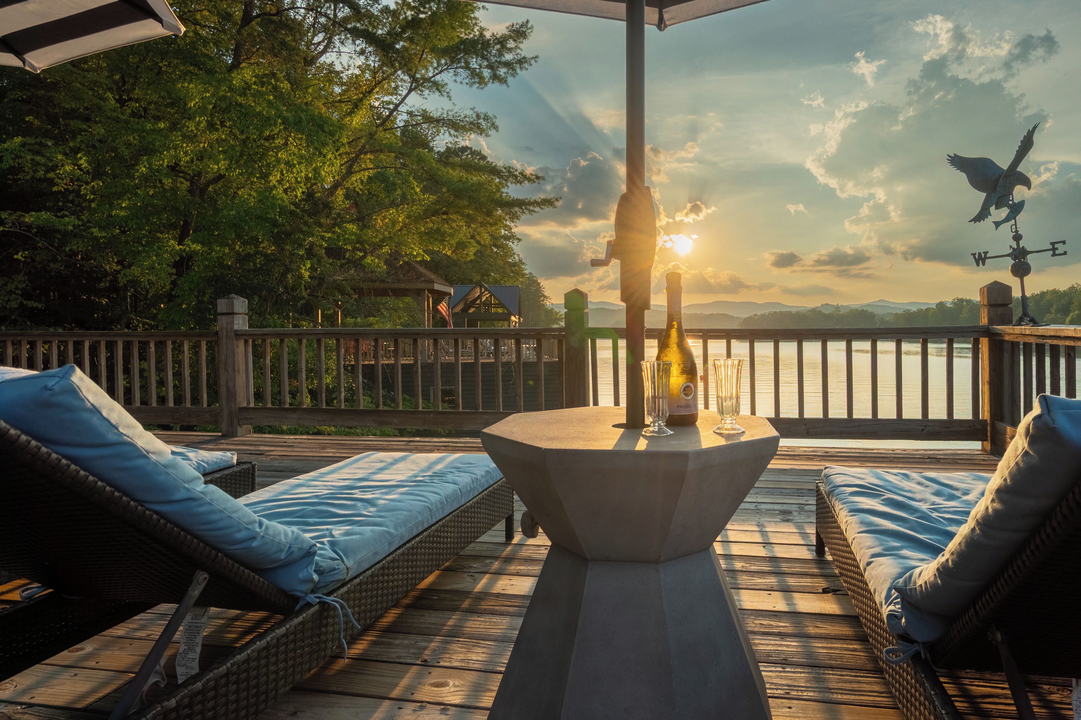 A deck with wicker furniture, a table, and a bottle of champagne.