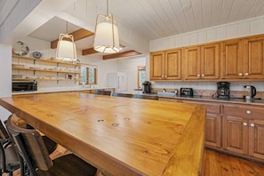 A kitchen with wooden cabinets, a large island, and hanging pendant lights.
