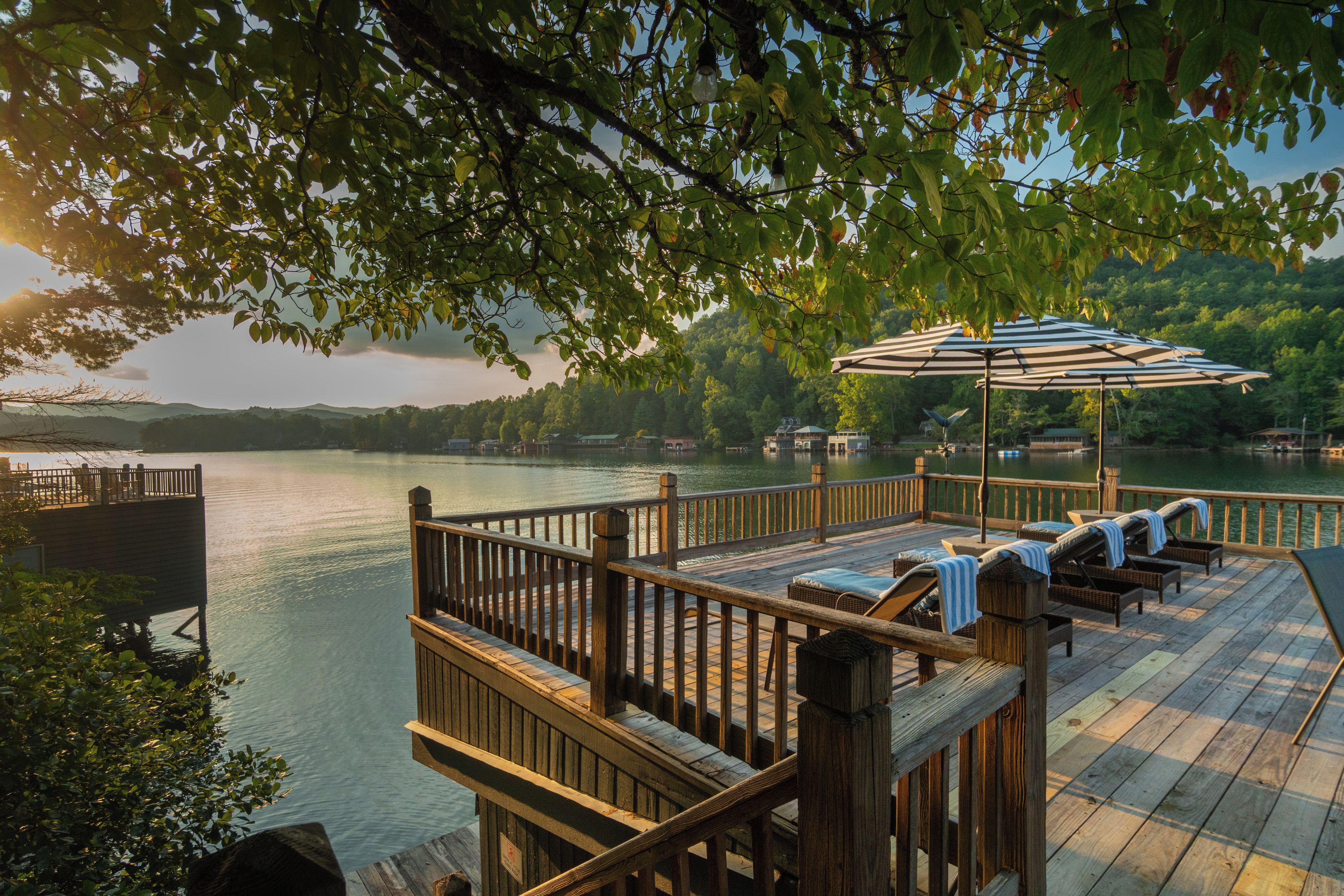 Une terrasse en bois avec des sièges extérieurs et une vue sur un lac.
