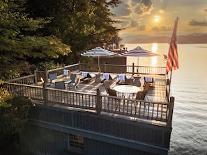 Eine Terrasse mit Sitzgelegenheit im Freien, einer Flagge und Blick aufs Wasser.