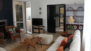 Un soggiorno con divano, poltrone, tavolino, televisore e zona pranzo con tavolo e sedie.