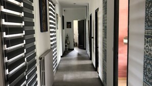 Un corridoio con termosifone, un quadro incorniciato e una porta che dà su una stanza dalle pareti decorate.