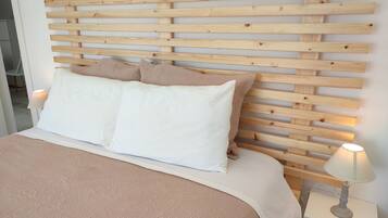 Een bed met een houten hoofdbord, witte beddengoed en een bedlampje.