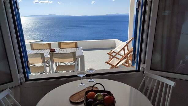 A room with a view of the sea, a table with a glass, a basket of fruit, and a chair. - Quiet private house with Sea view    (Sifnos)