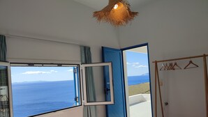 A bedroom with a large window offering a view of the sea and distant mountains. - Quiet private house with Sea view    (Sifnos)