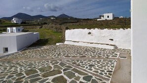 A rooftop with stone flooring, white buildings, and a mountainous landscape in the background. - Quiet private house with Sea view    (Sifnos)
