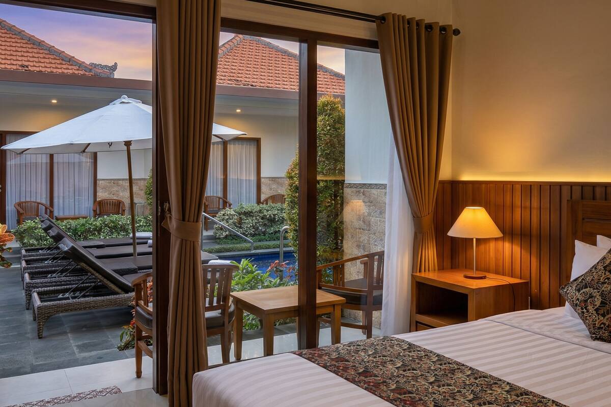 A hotel room with a bed, a desk, a chair, a pool view, and a balcony.