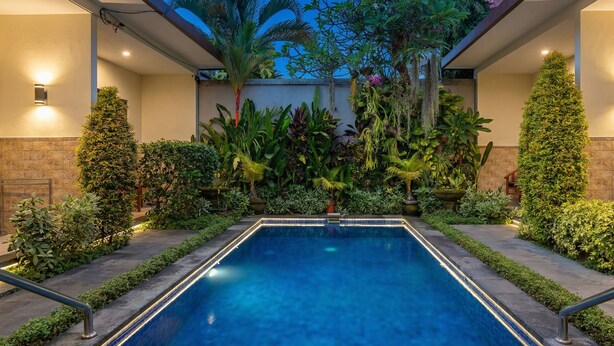 A rectangular pool with a tiled edge, surrounded by various plants and a stone wall. - Cening Ayu Sanur (Denpasar)