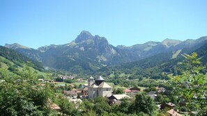 Un paysage montagneux avec un village, comprenant une église remarquable dotée d’un clocher.
