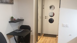 Espai vital reduït amb un sofà, una taula petita i una cadira. Es veu una porta amb tres miralls circulars.