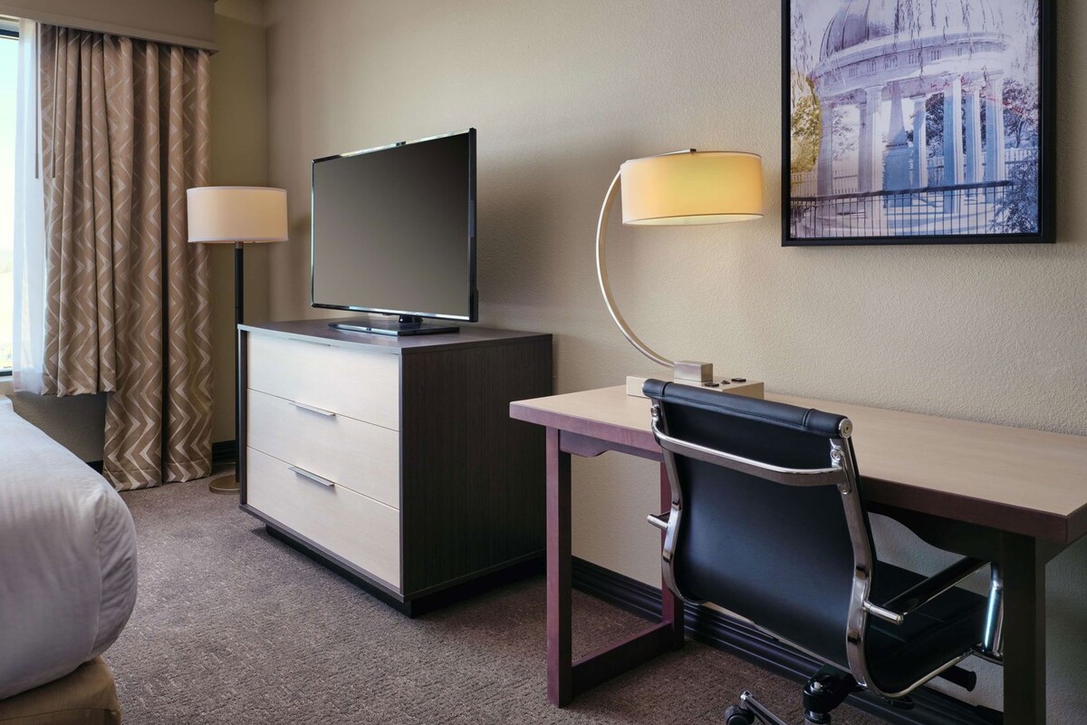 Une chambre d’hôtel équipée d’un lit, d’un bureau, d’une chaise, d’une télévision et d’une lampe.