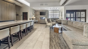 A spacious living area with a long bar, comfortable seating, and a large window providing a view of the outside. - Best Western Plus Executive Residency Jackson Northeast (Jackson)