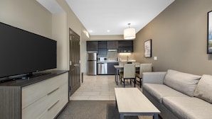 A modern living room with a flat-screen TV, a sofa, a coffee table, and a dining area with chairs and a table. - Best Western Plus Executive Residency Jackson Northeast (Jackson)