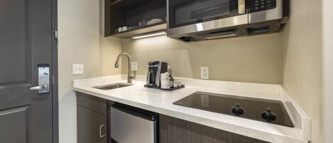 A modern kitchen with a stainless steel microwave, a built-in oven, a coffee maker, and a dishwasher.