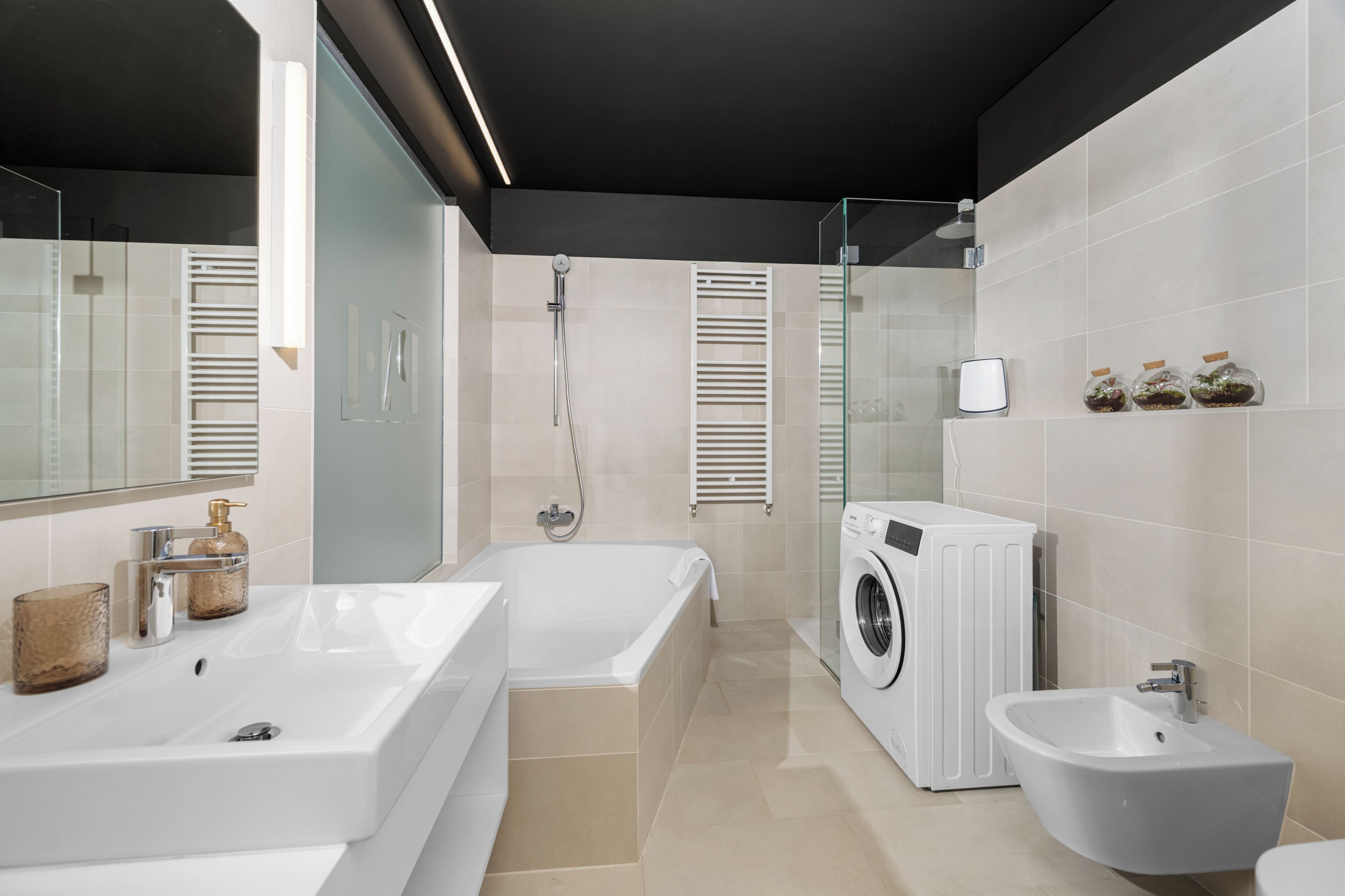 Ein modernes Badezimmer mit einer großen Badewanne, einem separaten Waschbecken, einer Waschmaschine und einem Bidet.