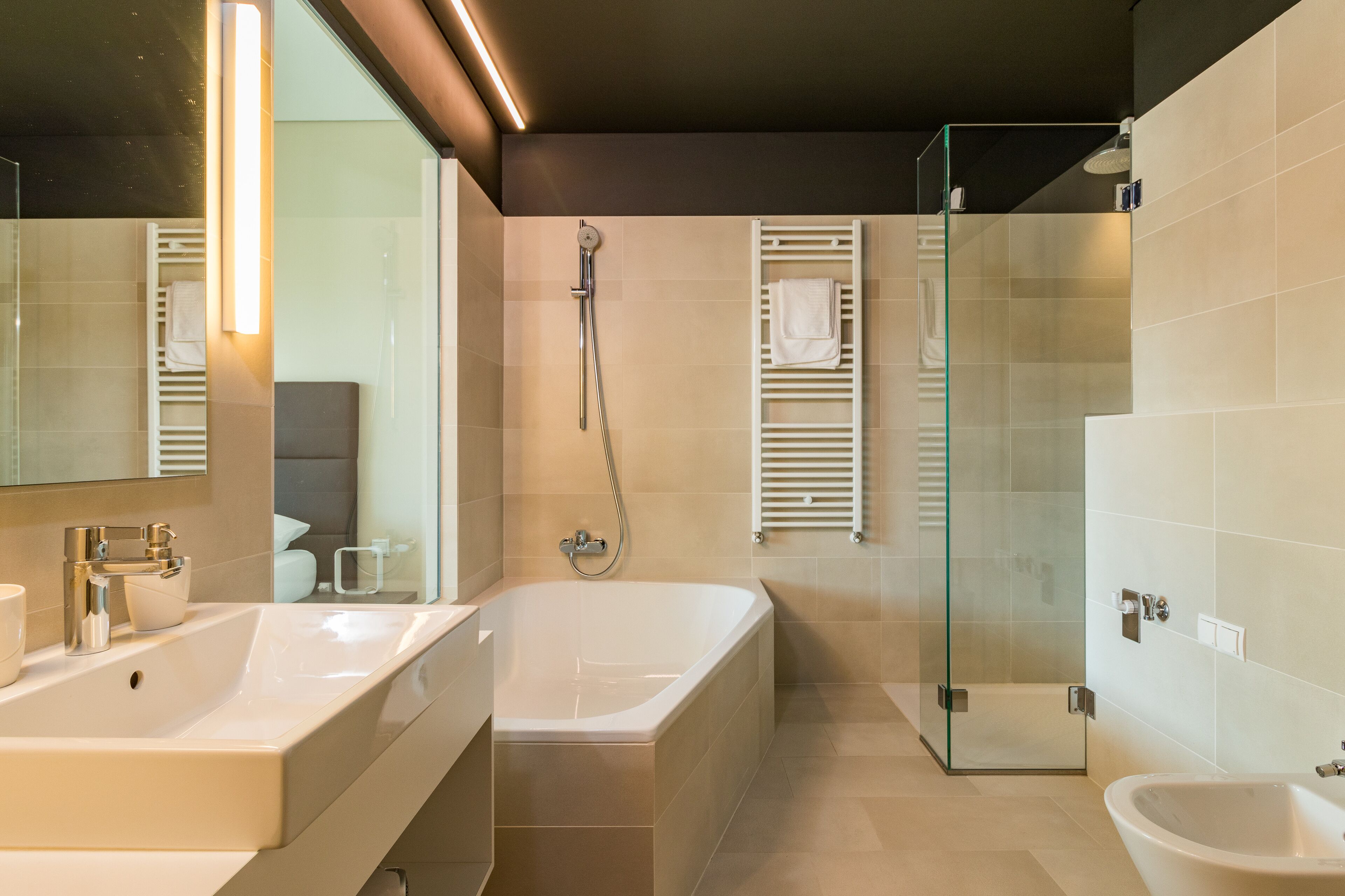 Une salle de bain moderne dotée d’une grande baignoire, d’une douche à parois de verre et d’un bidet.
